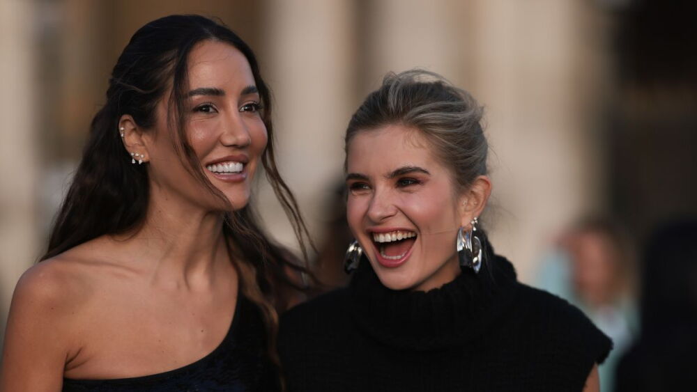 street style amara Kalinic lleva un top cruzado con lentejuelas negras, una falda larga blanca con cinturones negros, sandalias negras y un bolso Louis Vuitton negro y Xenia Adonts lleva un suéter negro con cuello alto, una falda blanca.jpg